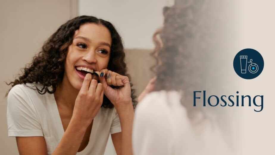 A teenage girl flossing her teeth.