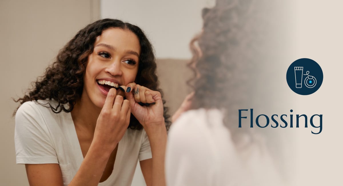 A teenage girl flossing her teeth.