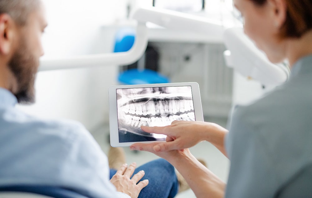 Rear view of man and dentist looking over dental X-rays