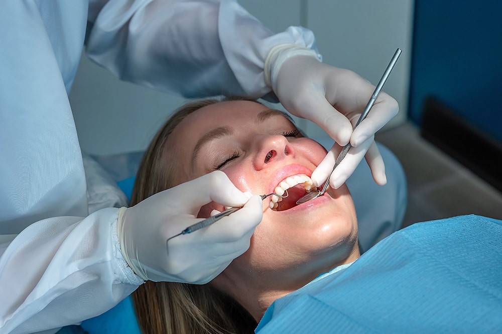 Dentist performing a routine preventative dental care using mirror and probe.