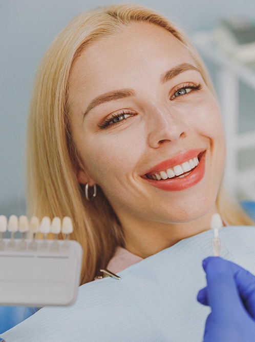 woman at the dentist choosing veneers enamel color palette with stomatologist compare teeth shade